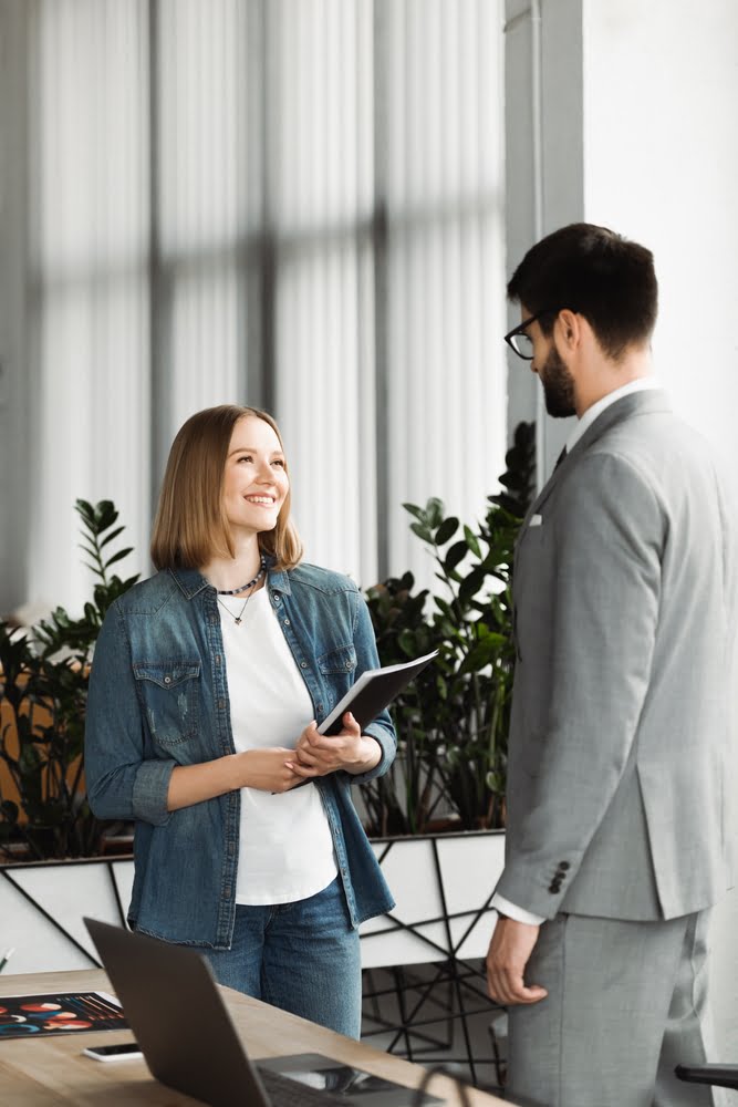 Smiling,job,seeker,holding,paper,folder,near,businessman,during,interview