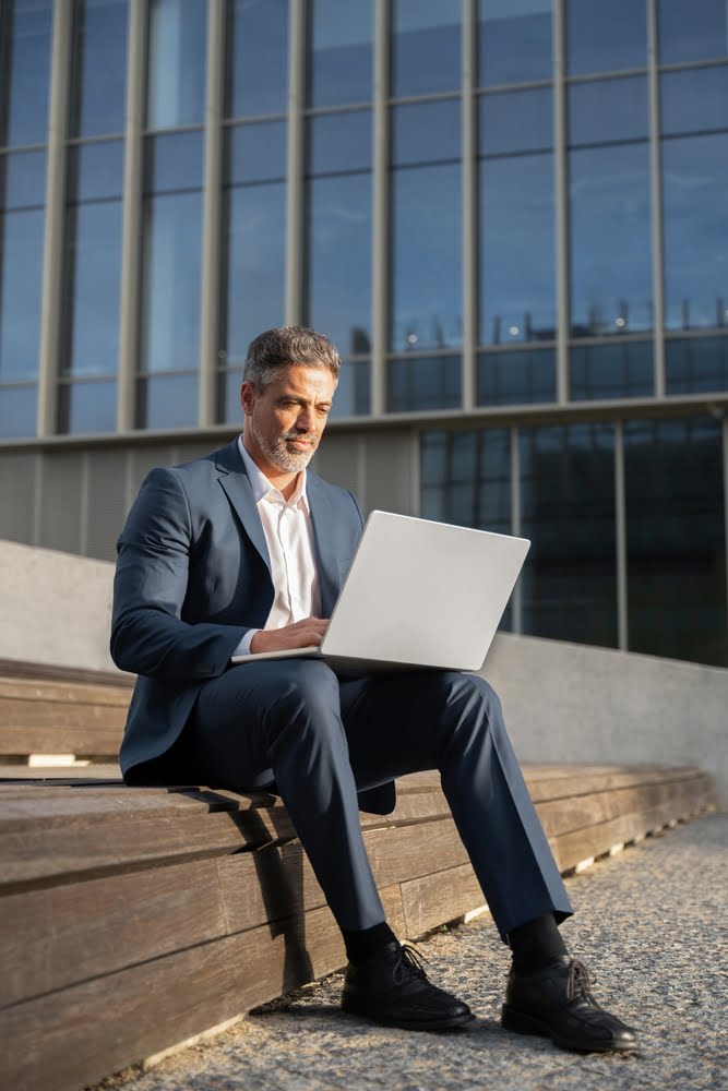 Focused,mature,successful,businessman,working,,typing,on,laptop,sitting,outdoors