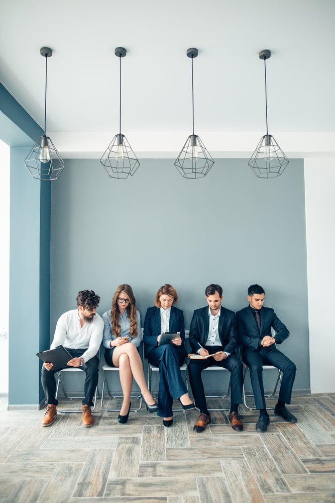 Business,people,waiting,for,job,interview,holding,phones,and,notepad